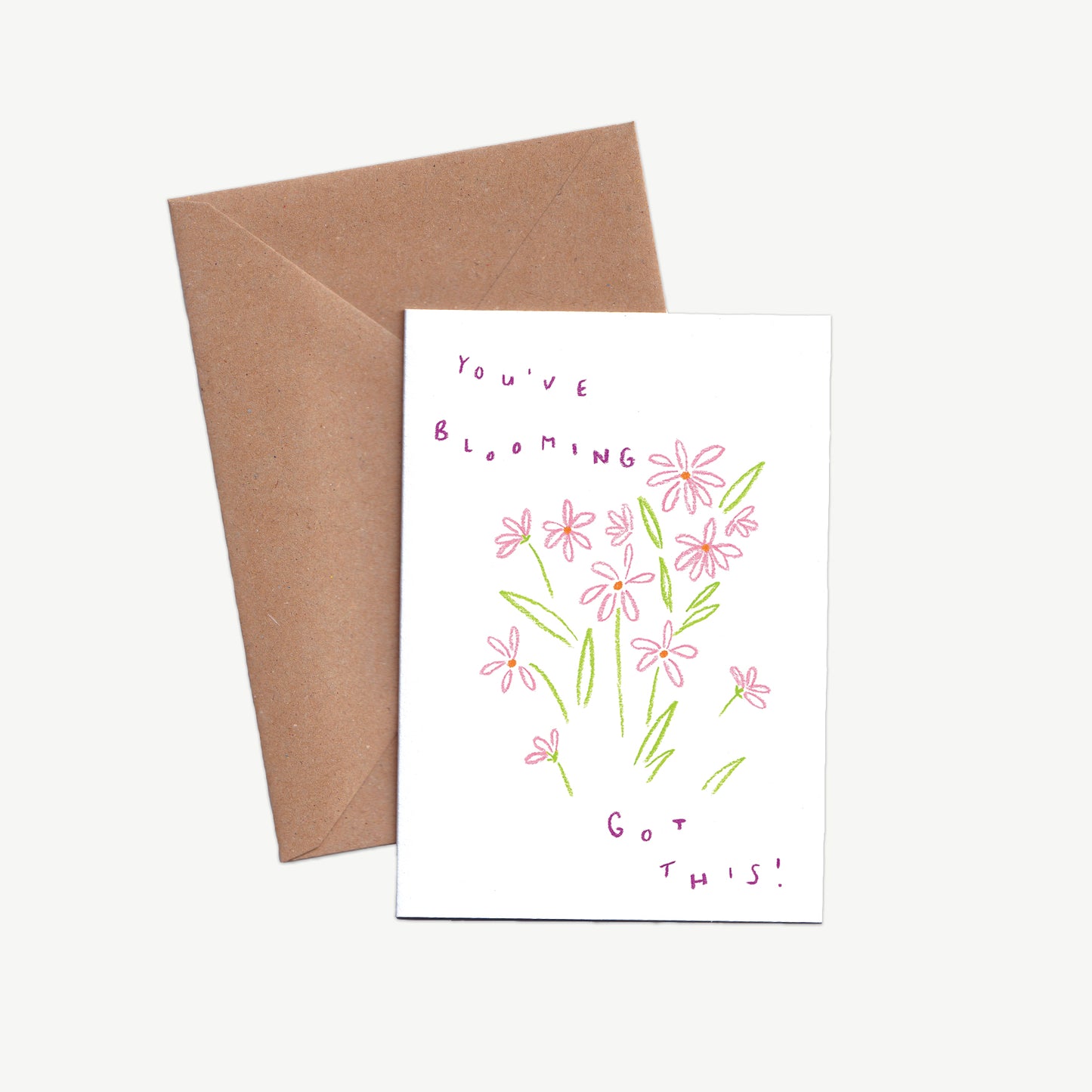 A Greetings Card with pink flowers and the words 'You've blooming got this' written in purple, drawn with pastel pencils, displayed with a kraft brown envelope